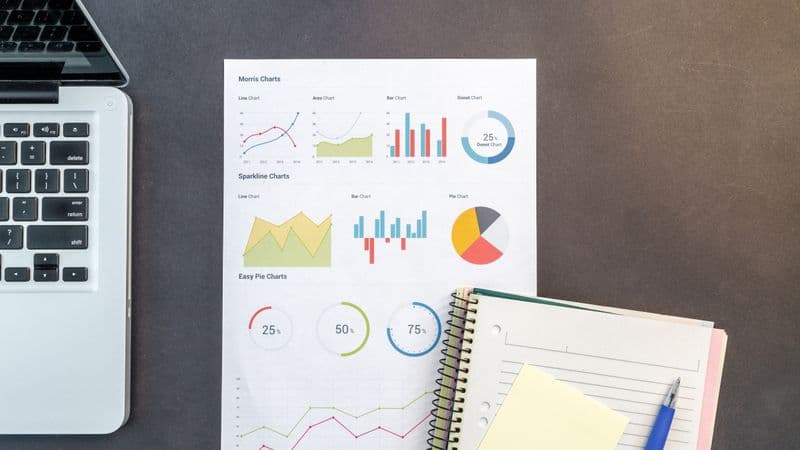 Top-down view of a desk with charts, a laptop, and notebooks, ideal for data analysis themes