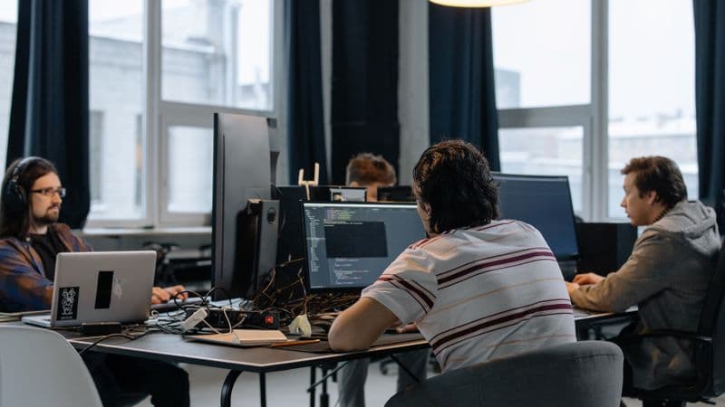 Team of developers working together on computers in a modern tech office
