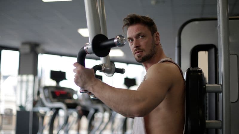 Focused man working out in a gym, showcasing biceps and determination
