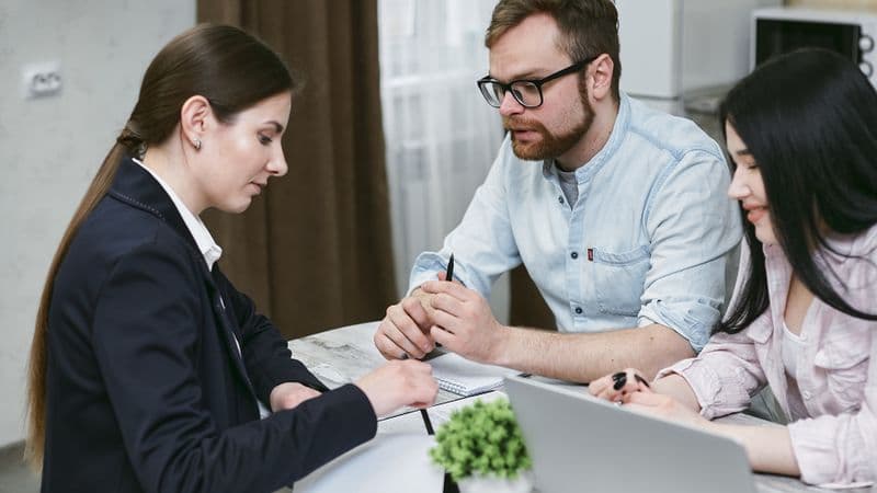 A couple discusses financial documents with their advisor, highlighting investment strategies