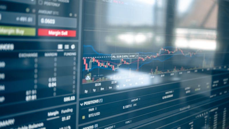 Trader analyzing forex charts on multiple screens