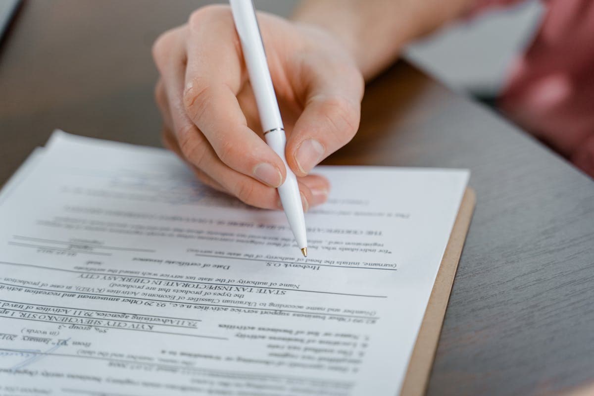 Stack of paper documents next to laptop showing digital text