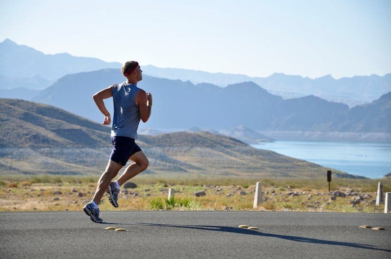 Runner checking a sports watch on a trail