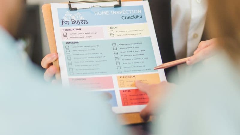 Close-up of hands holding a home inspection checklist clipboard for buyers